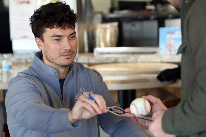 Justin Foscue signs a trading card and a baseball for a Rangers fan. Foscue is seeking his...