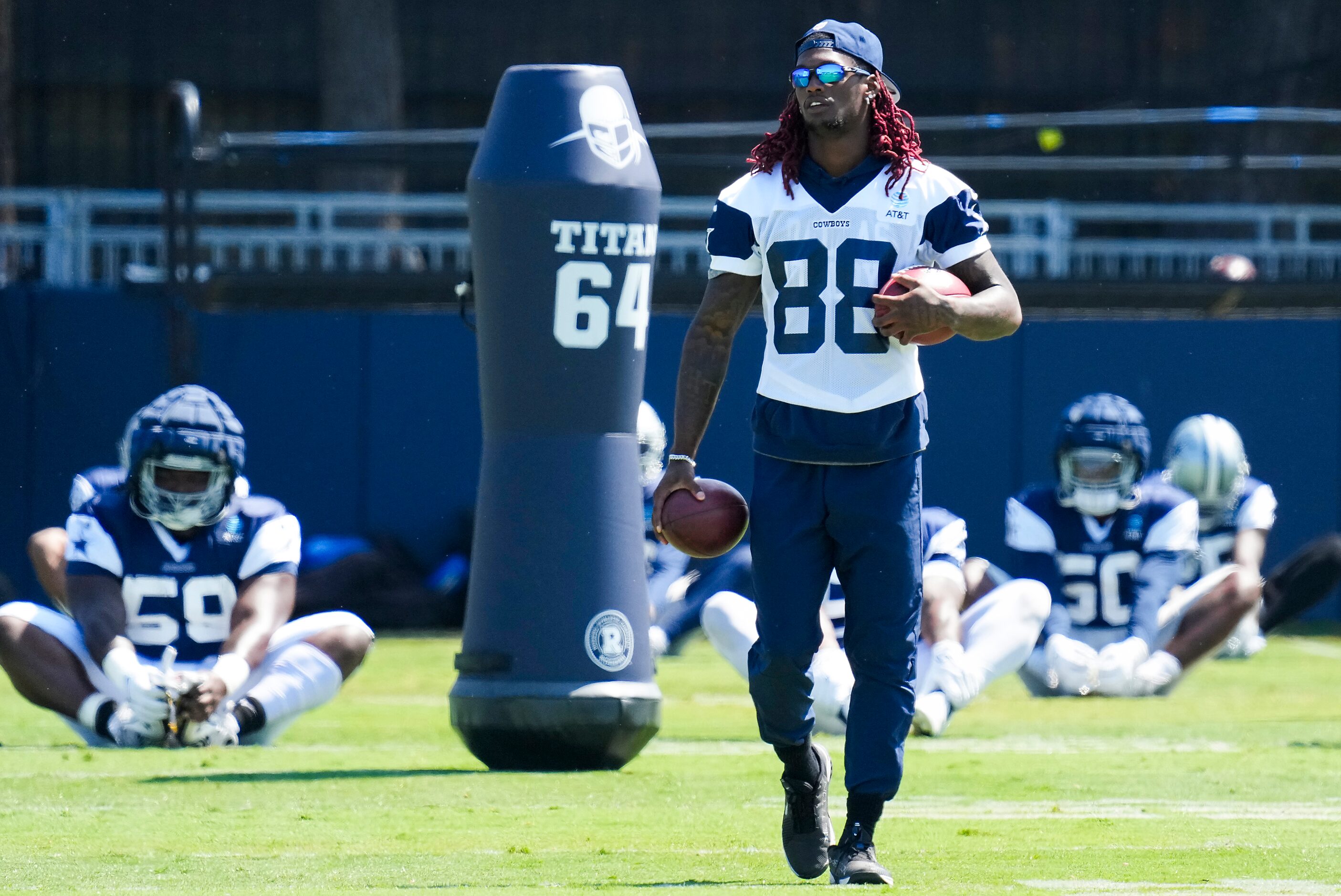 Dallas Cowboys wide receiver CeeDee Lamb walks on the field as teammates stretch during a...