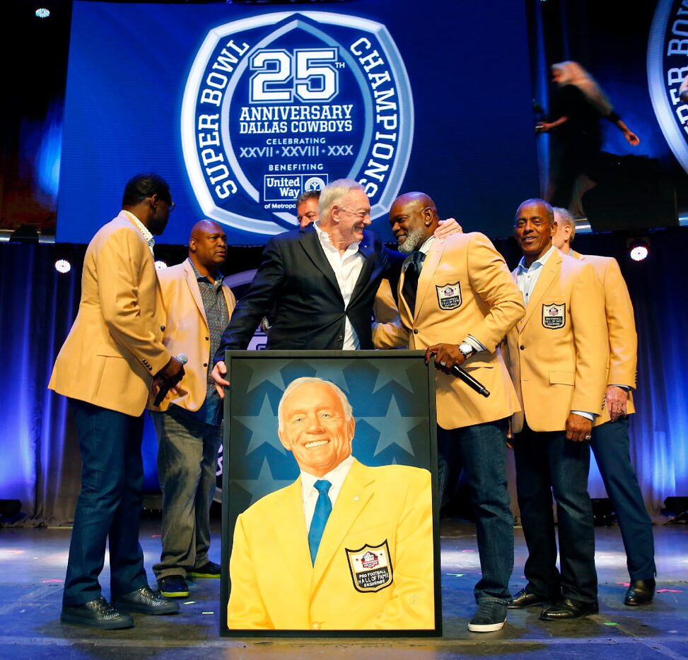 Dallas Cowboys owner Jerry Jones (center) gives a big hug to Emmitt Smith after a painted...