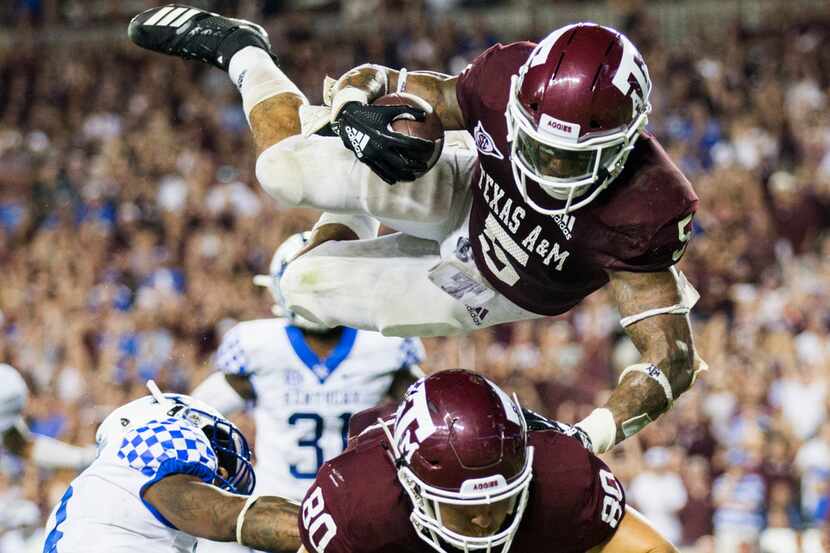 Texas A&M Aggies running back Trayveon Williams (5) is thrown in to the air as he runs to...