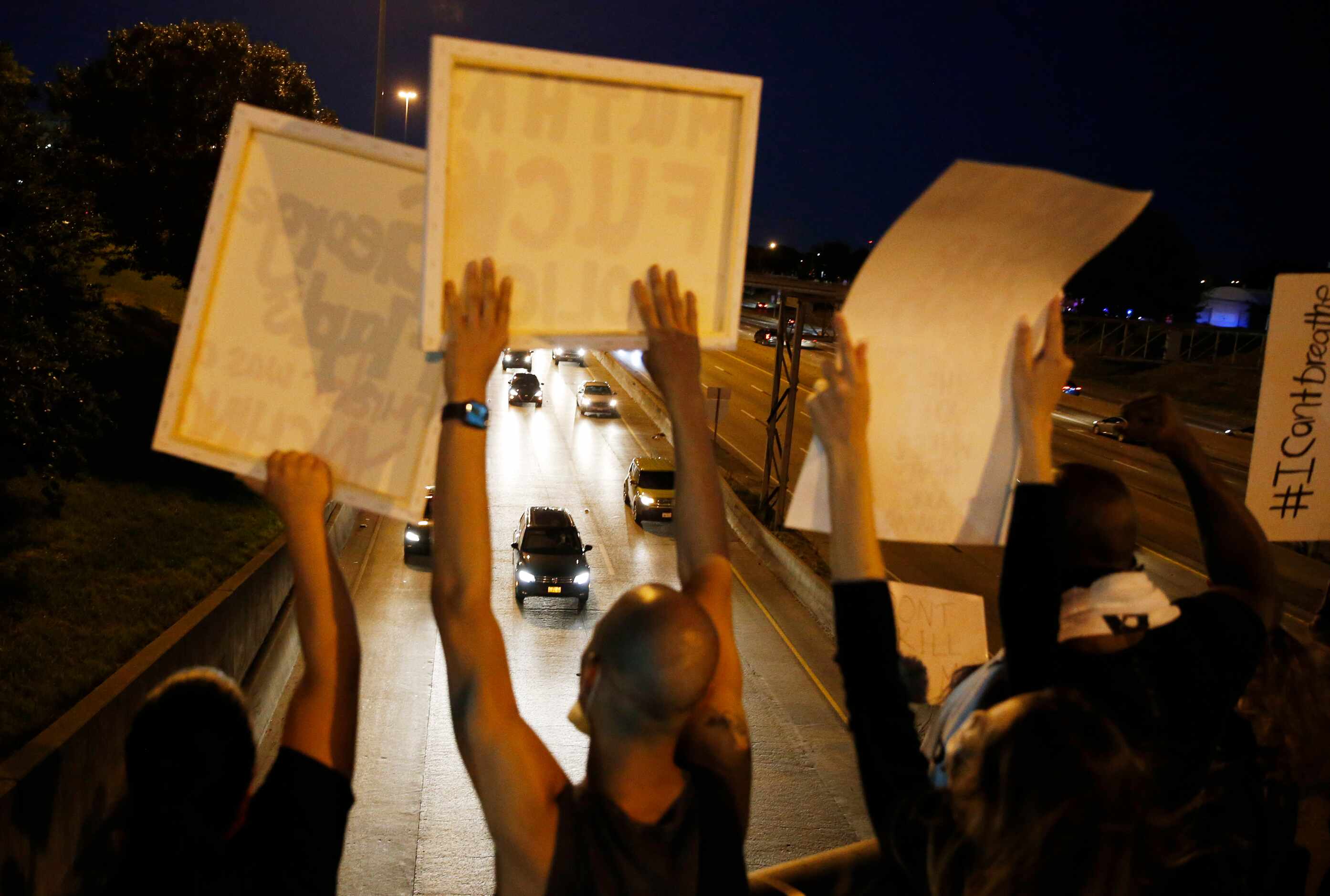 Protesters yell and cheer out on the Akard St. bridge to traffic along Interstate 30 during...