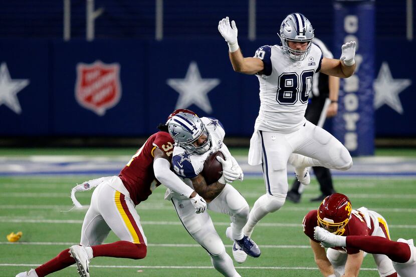 Dallas Cowboys running back Ezekiel Elliott (21) is wrapped up by Washington Football Team...