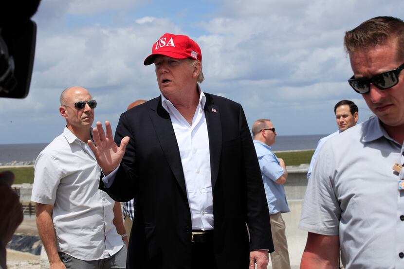 President Donald Trump, flanked by Secret Service agents, spoke to reporters during a visit...