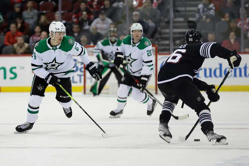 Dallas Stars center Roope Hintz (24) defends New Jersey Devils center Jack Hughes in the...