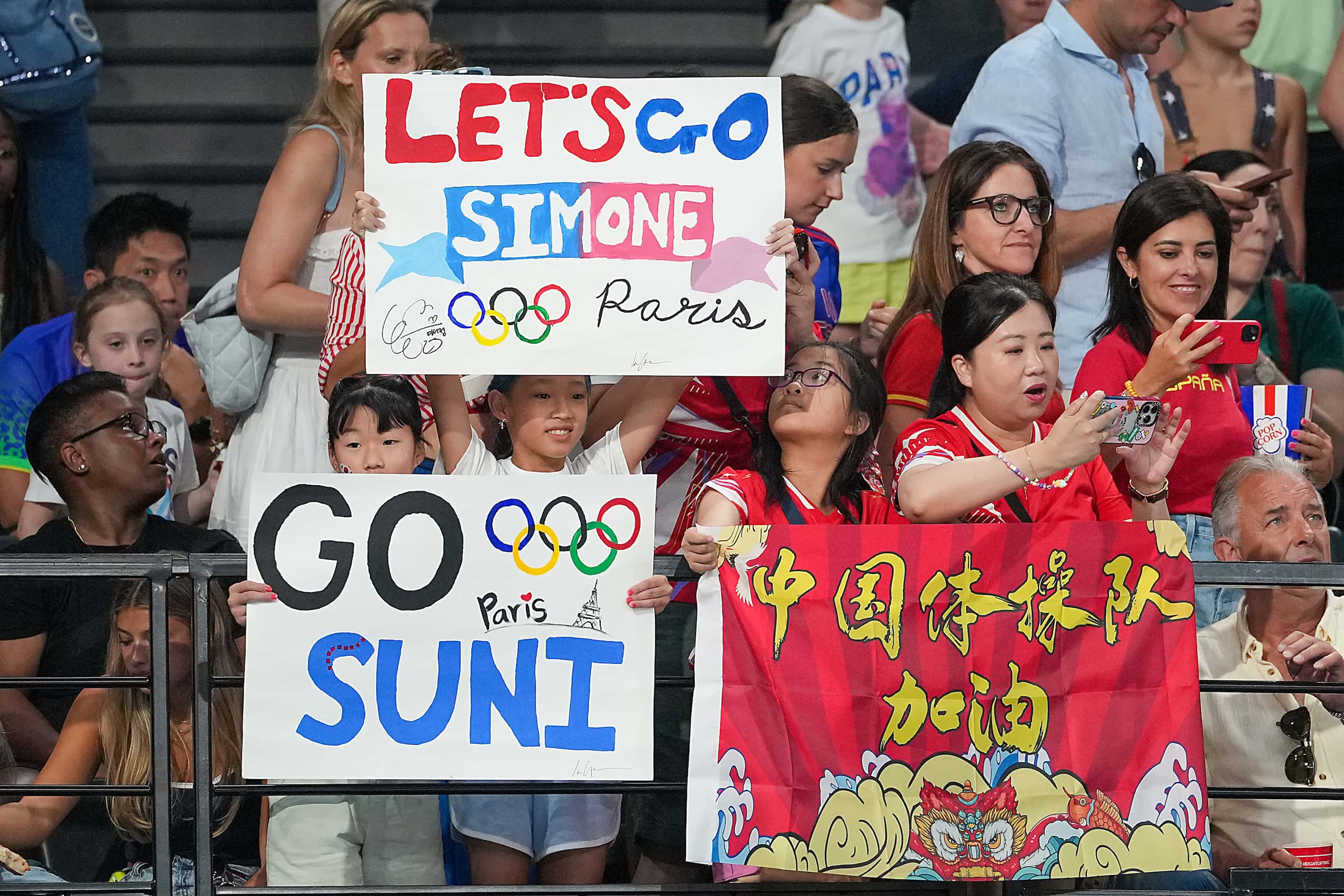 Fans cheer for Simone Biles and Suni Lee of the United States before the women’s balance...