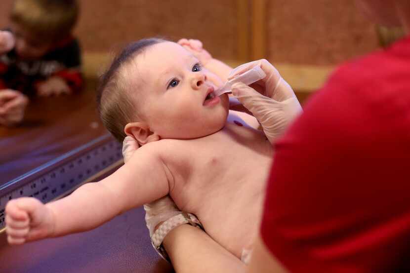 An oral vaccine is given to 6-month-old James Noland at Childhood Health Associates of...