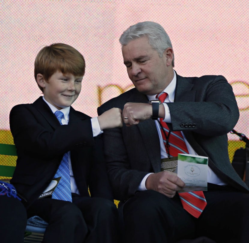 Kelcy Warren (right) fist bumps his son, Klyde Warren (center), as U.S. Rep. Eddie Bernice...