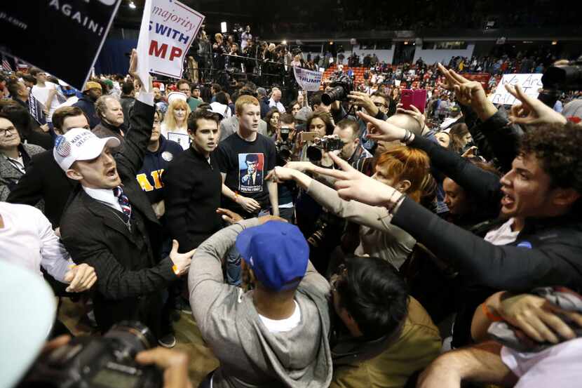 Supporters of Donald Trump, left, face off with protesters after a rally on the campus of...