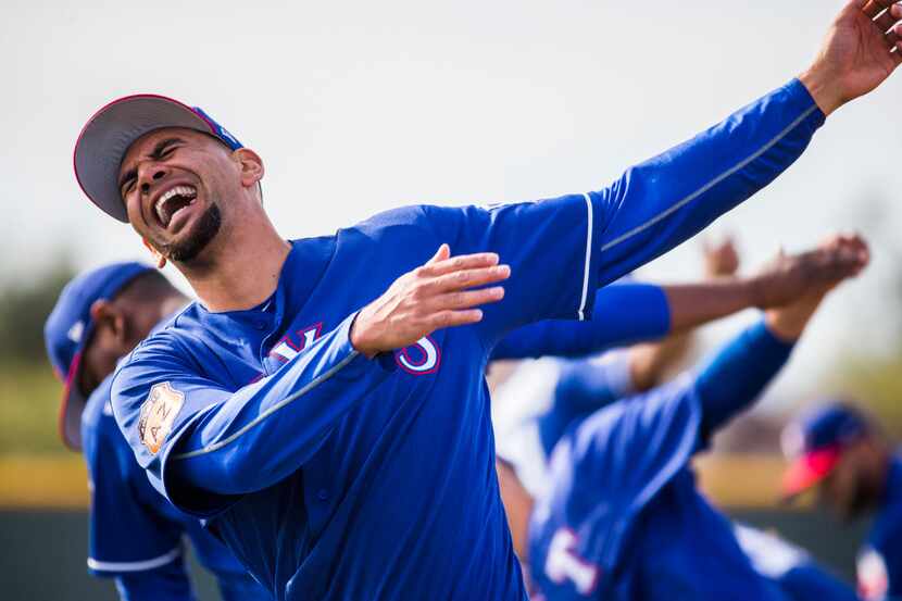 Texas Rangers starting pitcher Tyson Ross (44) laughs as he warms up during a spring...