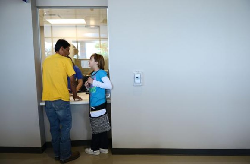 
Saul Chaparro and his daughter Ariadna Chaparro, 10, check in for her appointment at the...