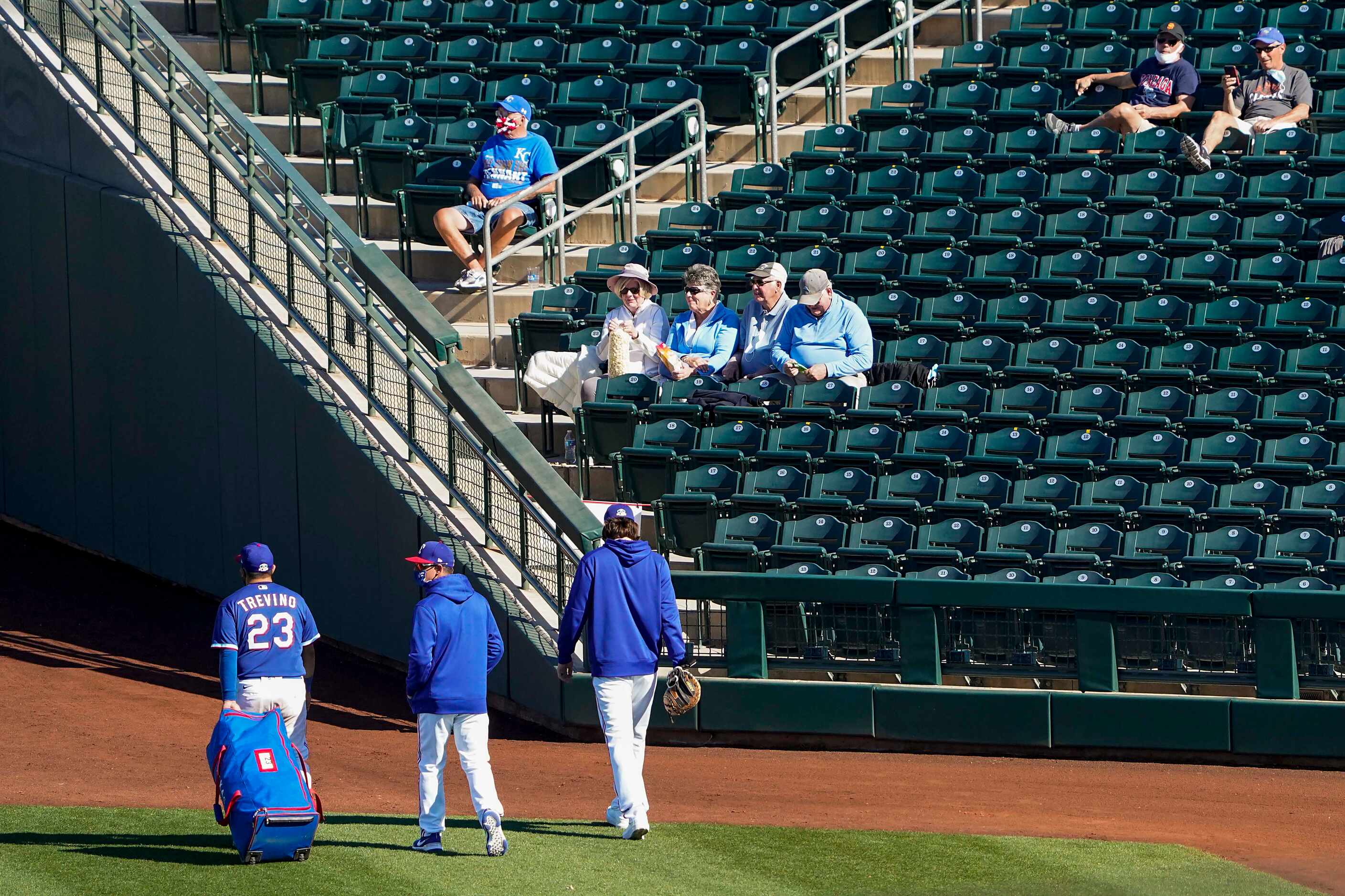 Texas Rangers catcher Jose Trevino heads to the clubhouse past fans seated in socially...