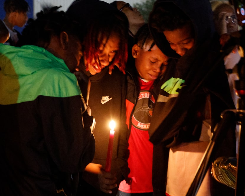 Teammates of 11-year-old De’Evan McFall comfort each other after a balloon release in memory...