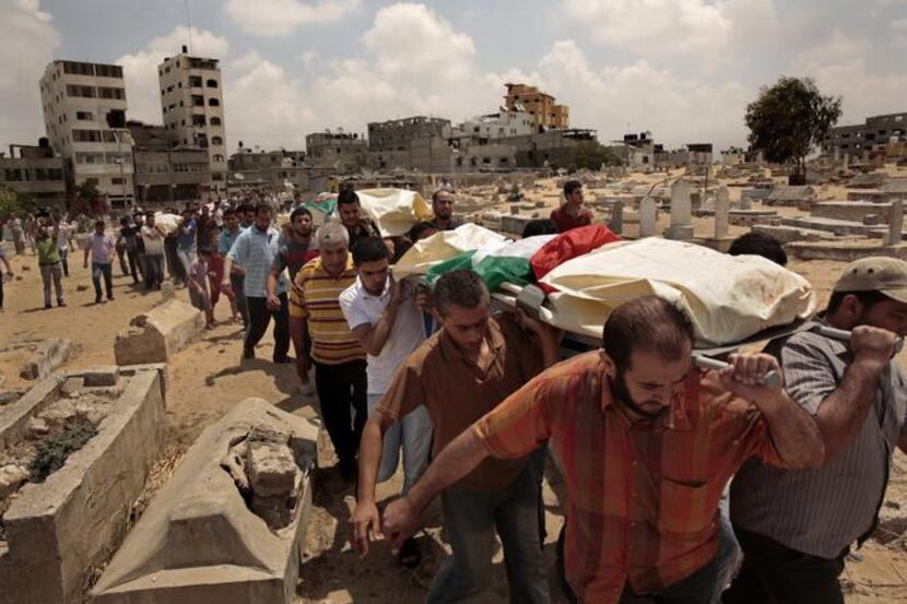 
Palestinian friends and family gathered Monday to bury their dead at a cemetery in the Gaza...