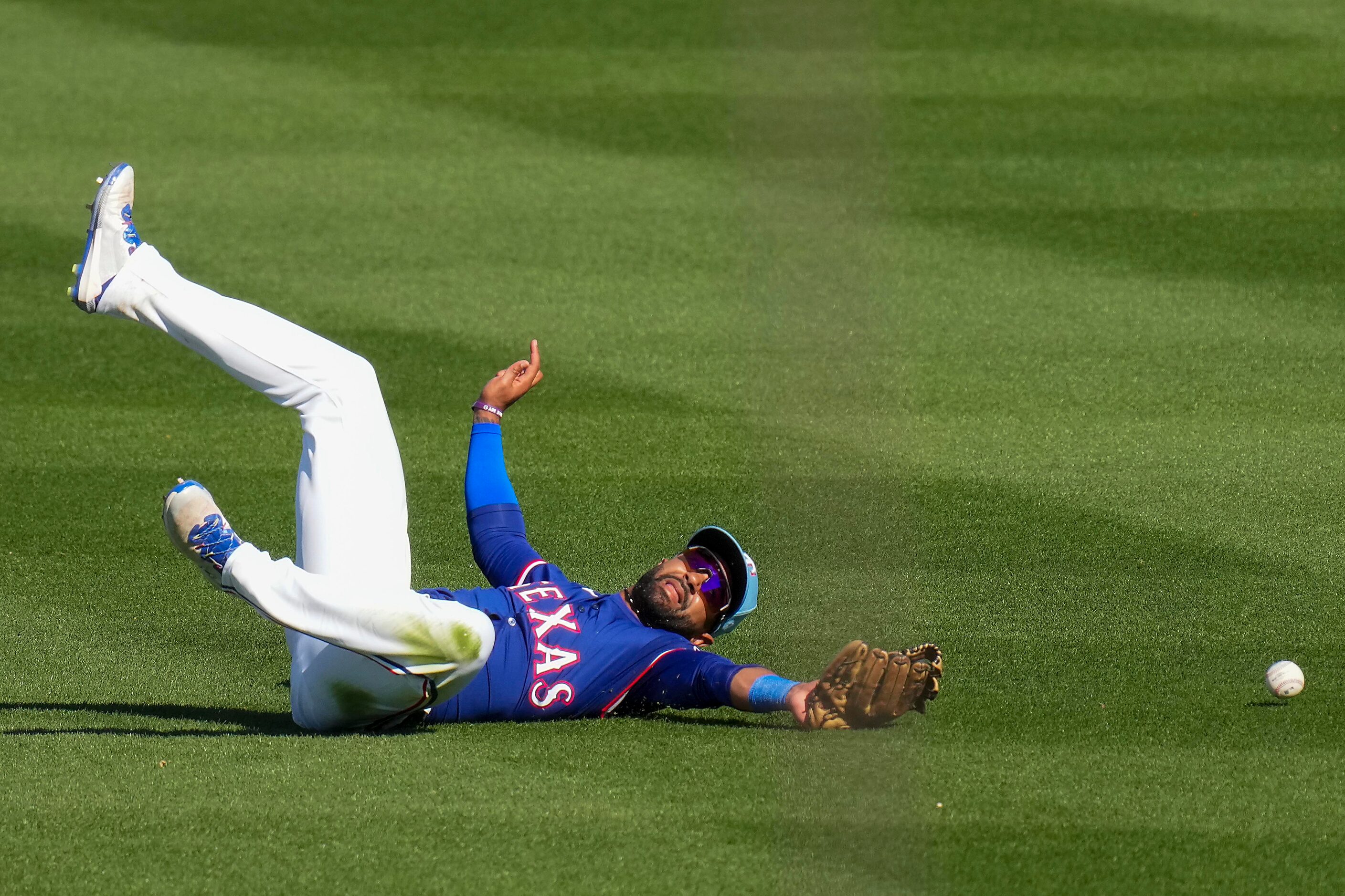 Texas Rangers outfielder Derek Hill can’t make a diving catch on a single by the Kansas City...