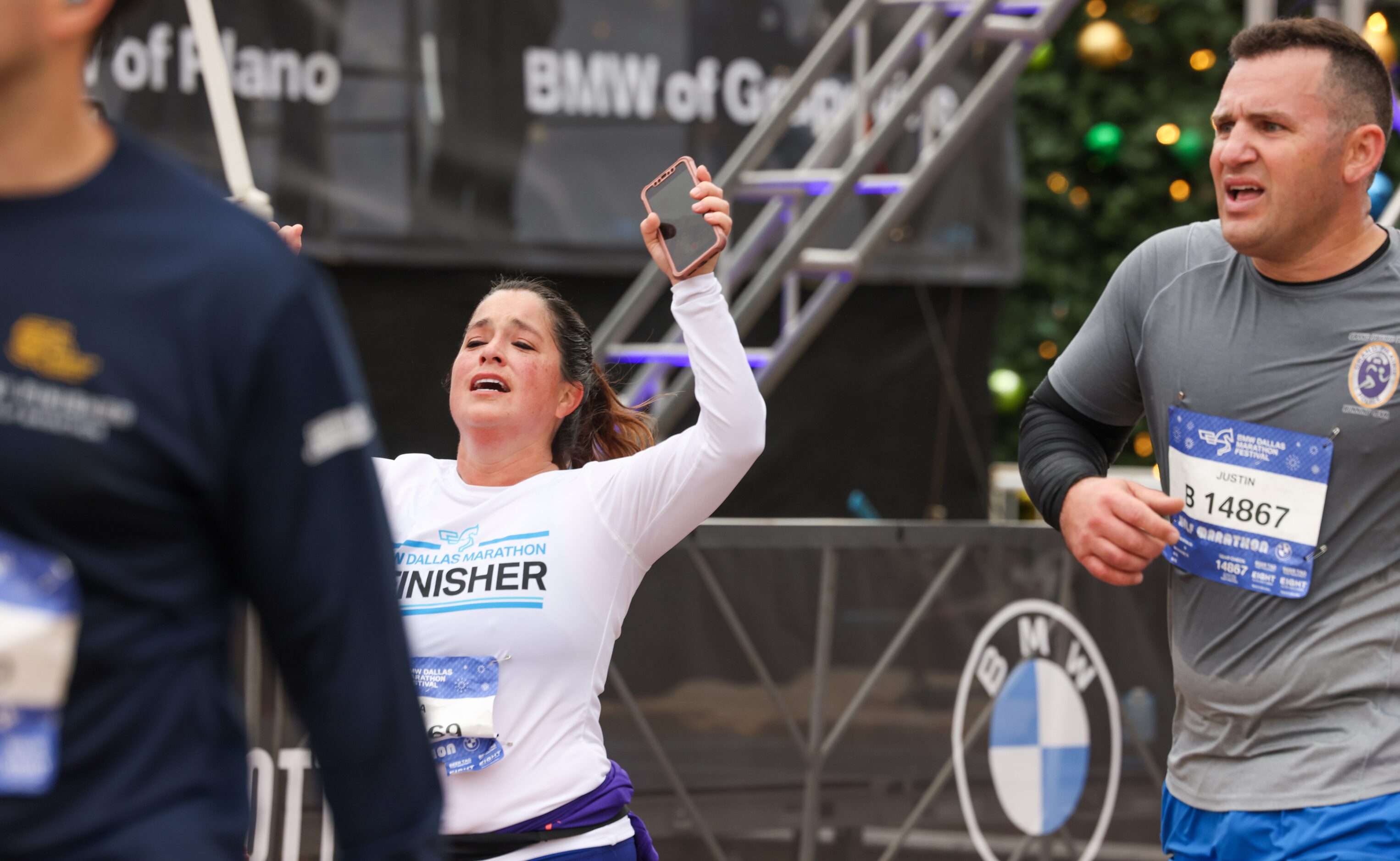 Half-marathon runners celebrate crossing the finish line at the BMW Dallas Marathon on...