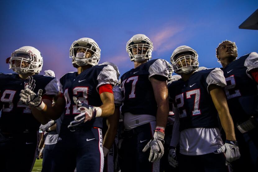 Allen football players watch their teammates from the sideline during the second quarter of...