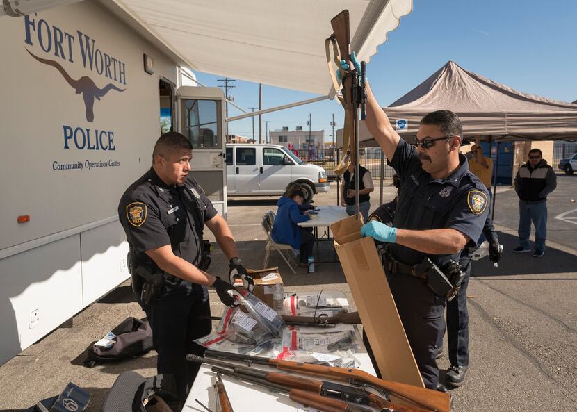 Fort Worth Police officers J.M. Aguilar (left) and R. Delos Santos collect weapons during a...