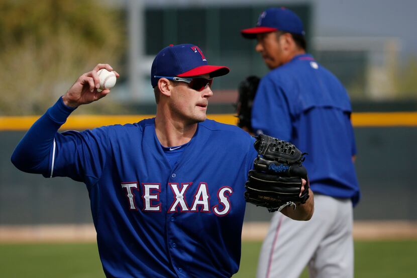 Texas Rangers pitcher Jamey Wright fields a ball during a drill throwing to first base after...
