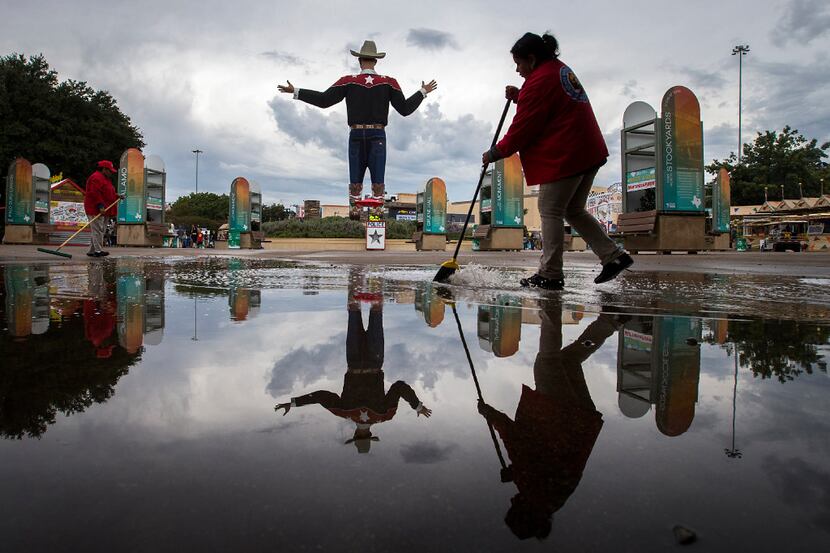 Fair employees sweep water toward drains as they work to clear standing water after a...
