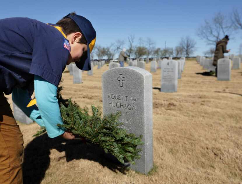 8-year-old Ace Freeman places a wreath as part of a Wreaths Across America event at D-FW...