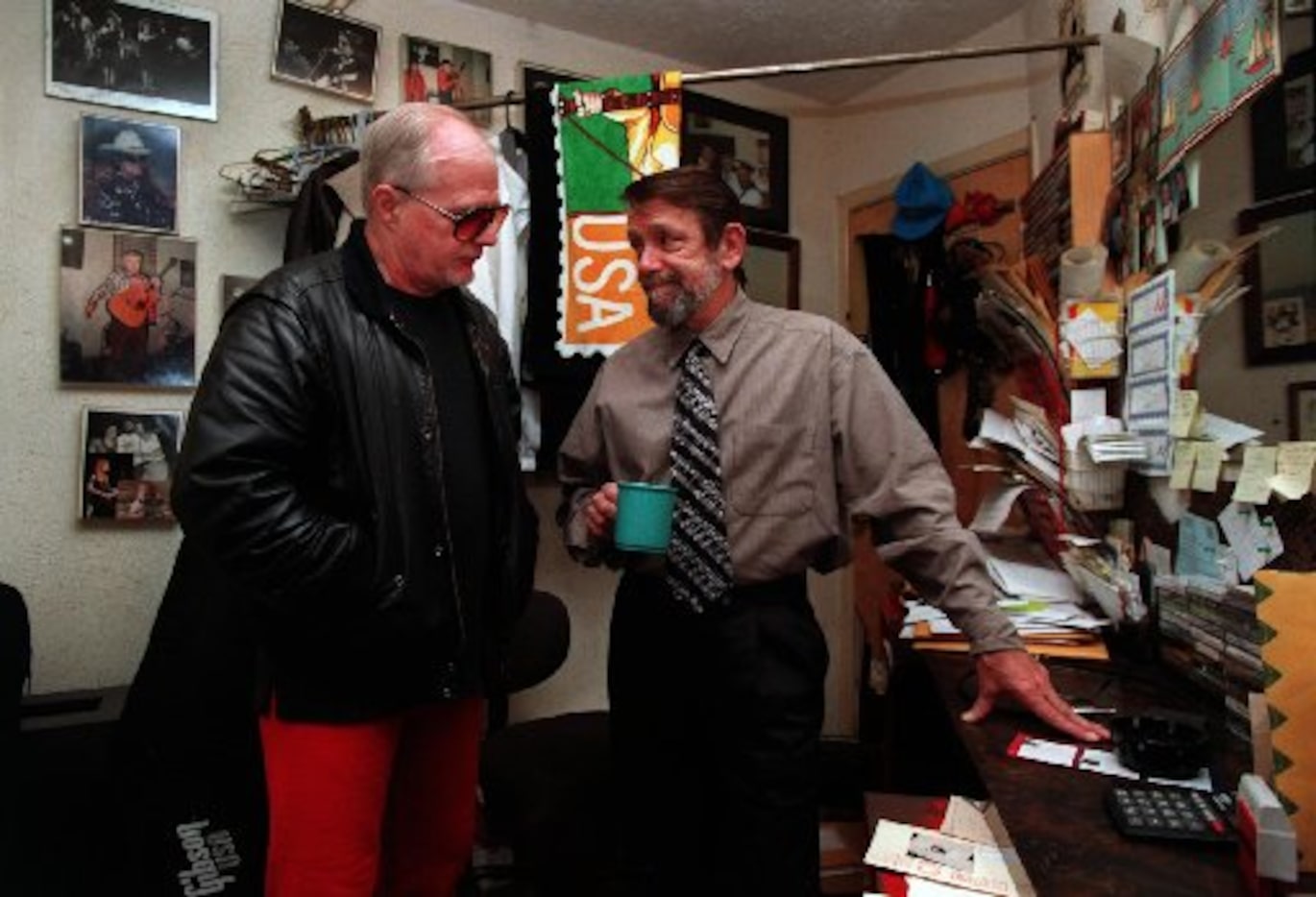 In his tiny office at Poor David's Pub on  Lover Greenville owner David Card, right, goes...