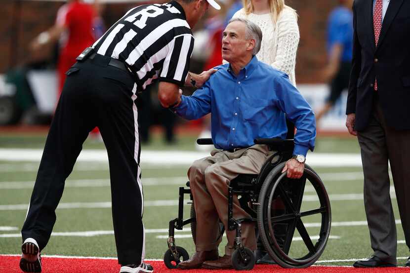 Greg Abbott, then attorney general of Texas, greets an official at midfield before the...