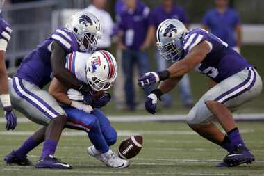 Louisiana Tech wide receiver Trent Taylor, middle, fumbles while tackled by Kansas State...