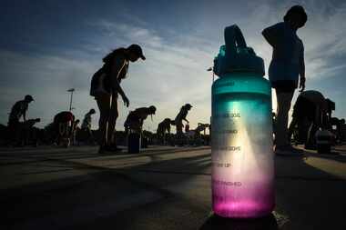 Members of the Coppell marching band pause for a drink of water during a morning practice at...
