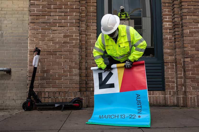 Joseph Alberts rolls up a South by Southwest banner after it was removed from a lamp post in...