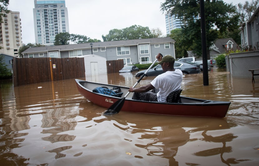 An unidentified man paddles a canoe to rescue residents and their belongings at a flooded...