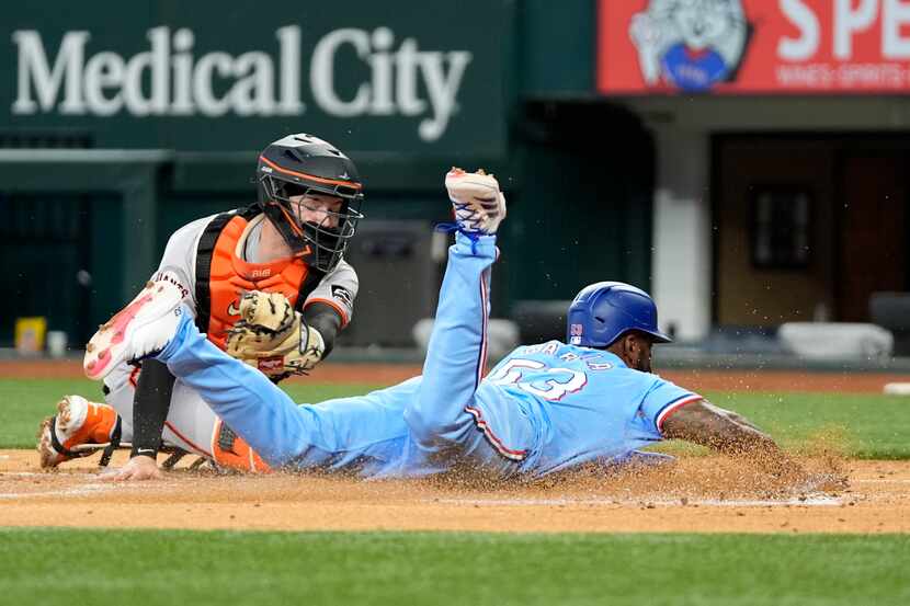 Texas Rangers' Adolis Garcia slides steals home ahead of the attempted tag by San Francisco...