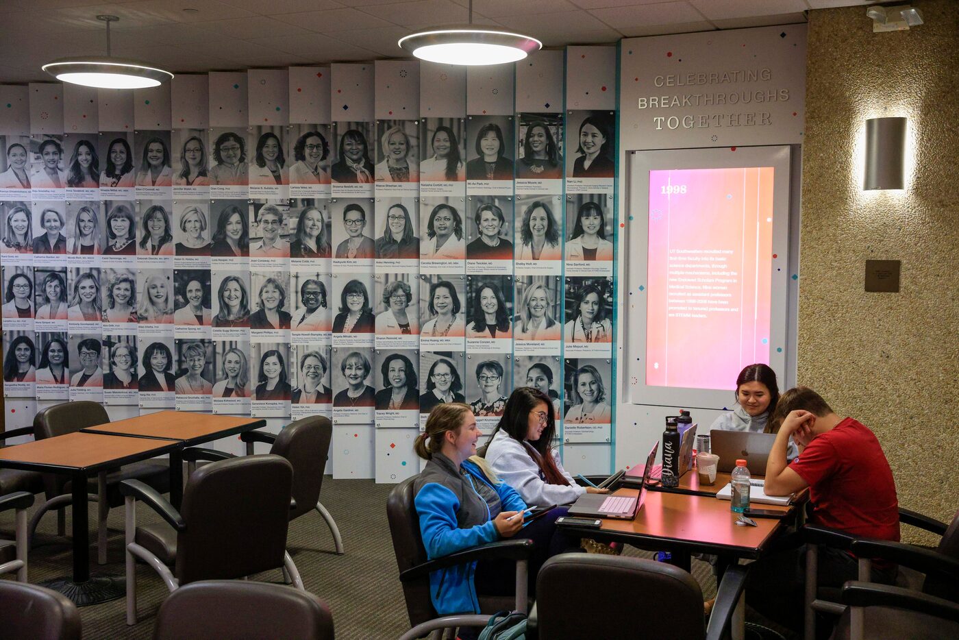 Students studying to be physician assistants study in front of a display celebrating female...