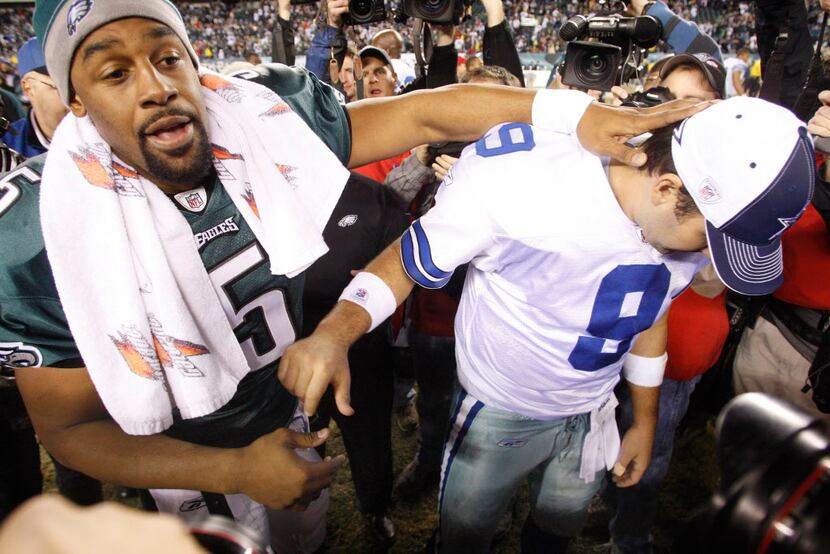 Donovan McNabb, left, meets a distraught Tony Romo at mid-field after the Dallas Cowboys...