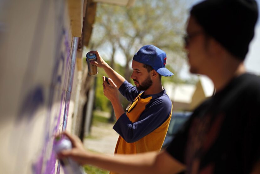 Isaac Davies worked from a design on his phone as he and other graffiti artists painted the...