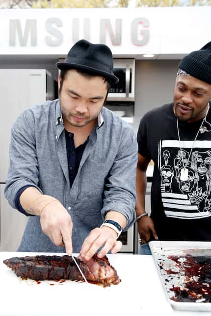 Chef Paul Qui (left) slices meat while singer/songwriter D'Angelo looks on at SXSW 2015 in...