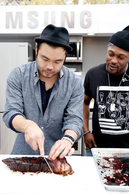 Chef Paul Qui (left) slices meat while singer/songwriter D'Angelo looks on at SXSW 2015 in...