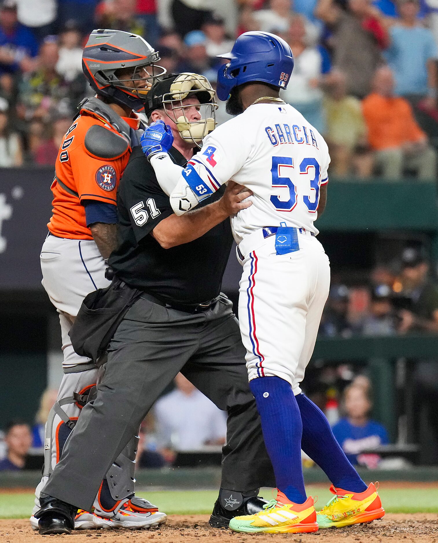 Umpire Marvin Hudson (51) tries to separate Texas Rangers right fielder Adolis Garcia (53)...