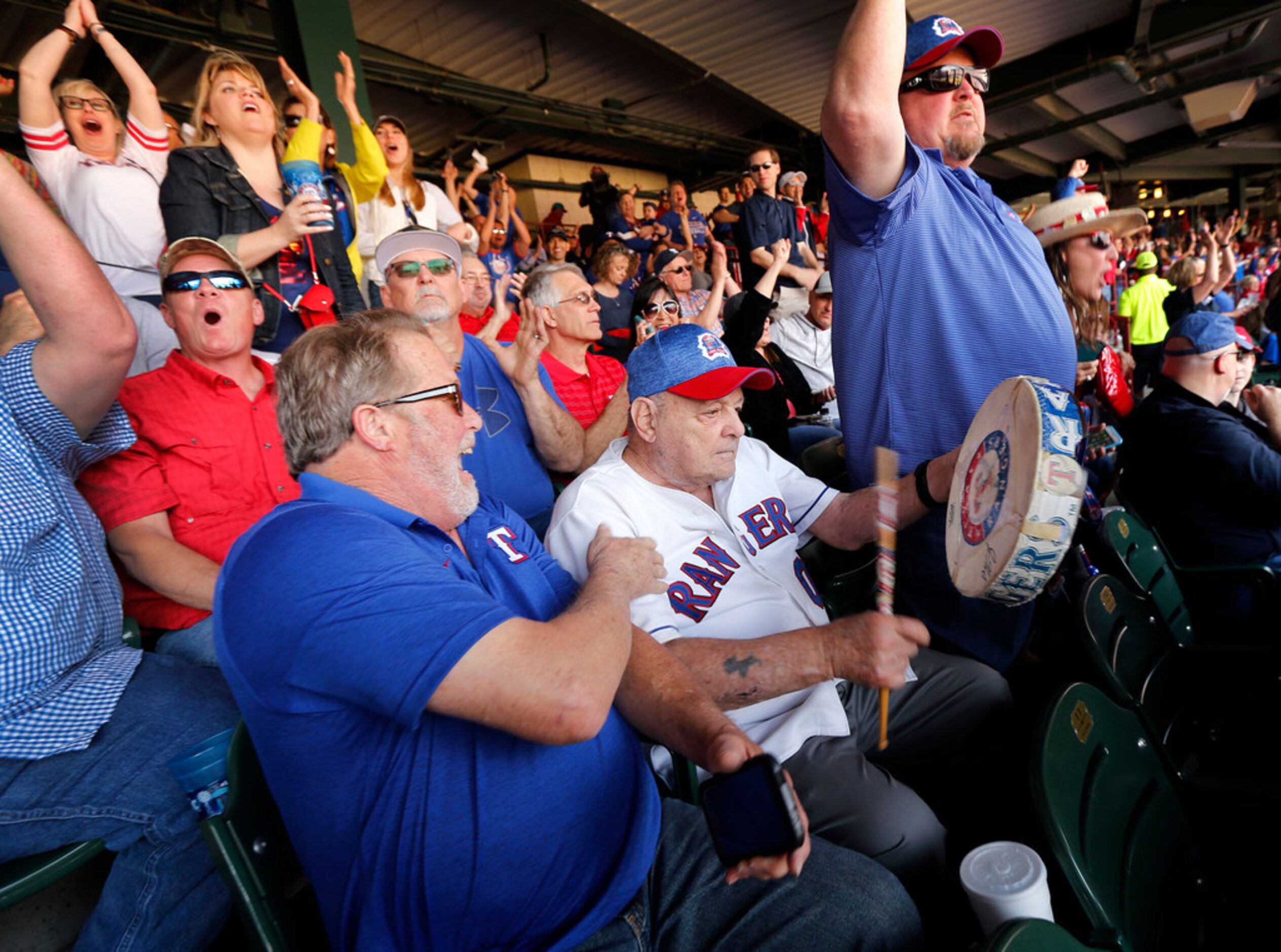 Zonk aka John Lanzillo Jr., 85, (center) beats on his worn drum after Texas Rangers batter...