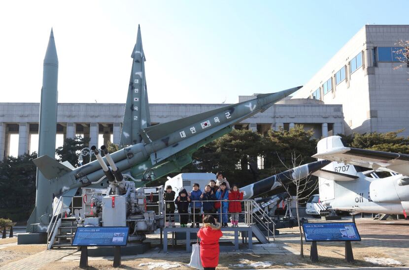 Kindergartners pose for pictures in front of a mock North Korean Scud-B missile (left) and...