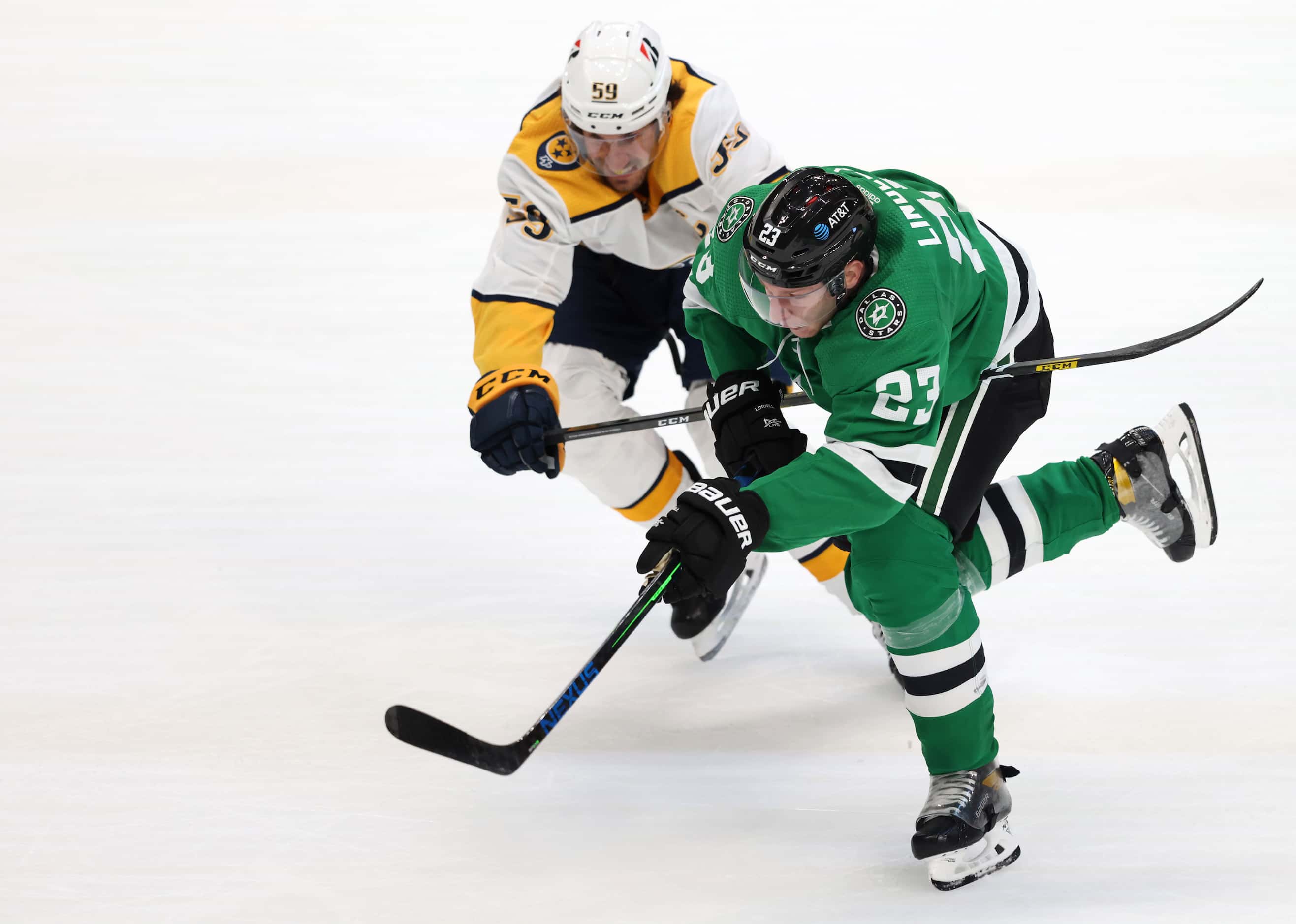 Dallas Stars defenseman Esa Lindell (23) races towards the puck as he is defended by...