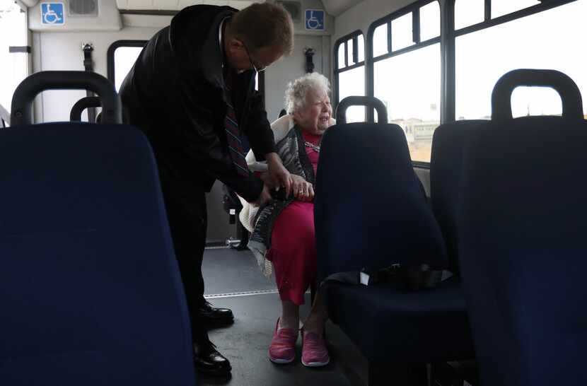 Envoy America driver Kris Werner helps Jeannyne Reston with her seatbelt on the bus at The...