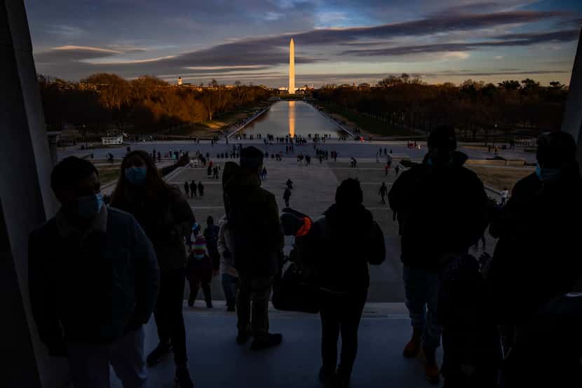 Visitors look out from the Lincoln Memorial across the Reflecting Pool toward the Washington...