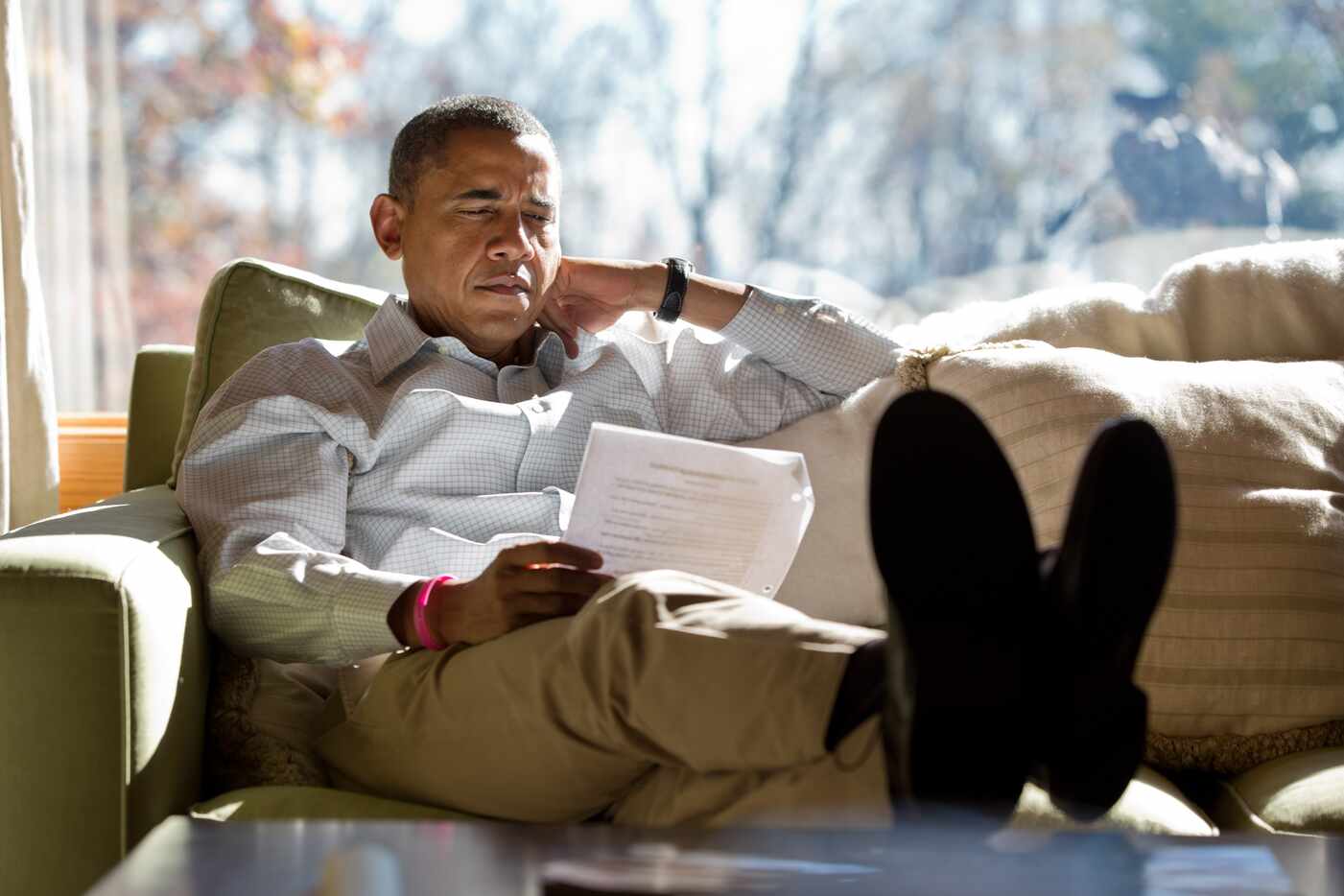 President Barack Obama reads briefing material while meeting with advisors inside his cabin...