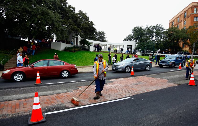  Dallas city workers repair the asphalt on Elm Street in Dealey Plaza as people visit Dealey...