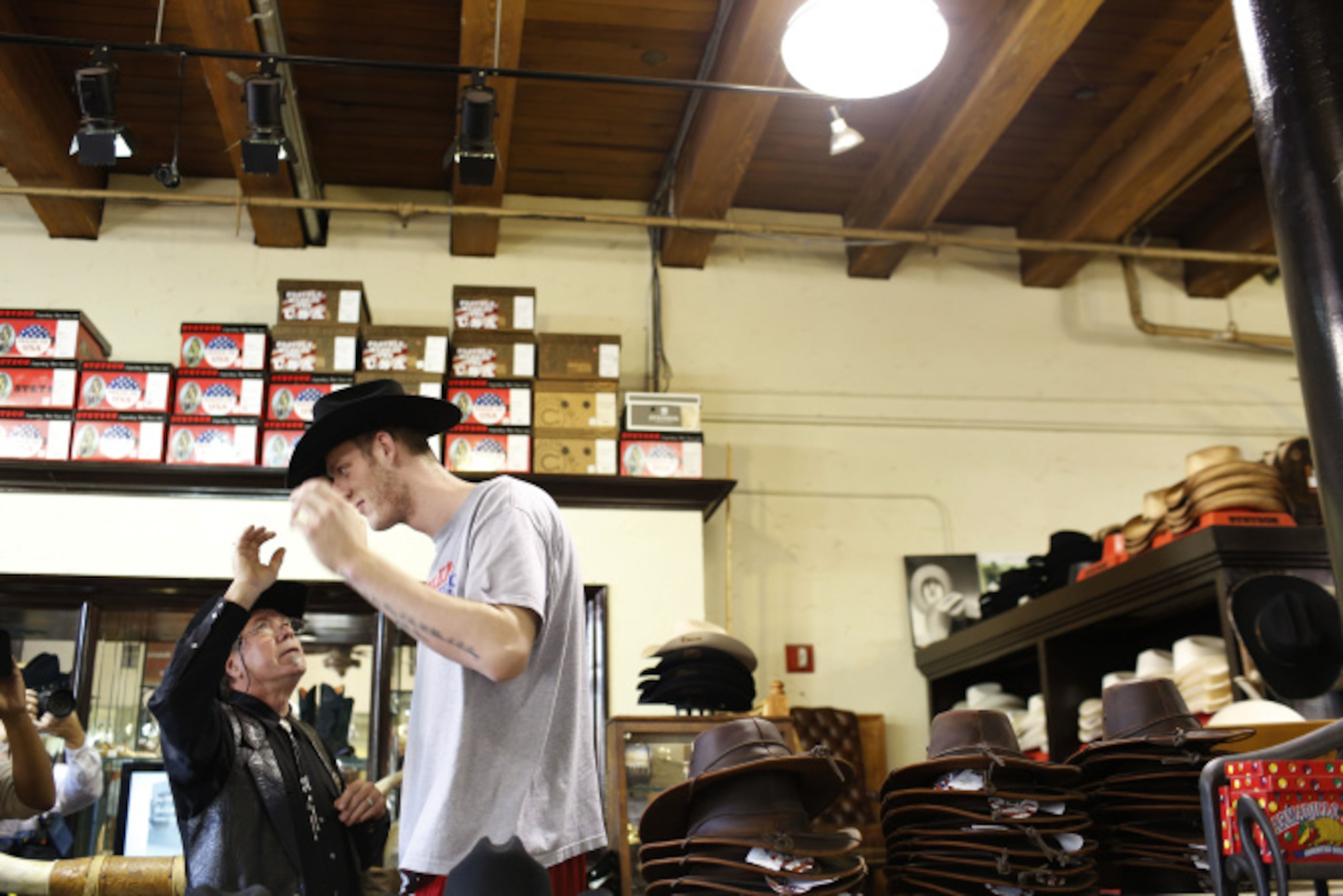 Store owner Bill Dewbre places a hat on Harlem Globetrotter Paul "Tiny" Sturgess' head at...