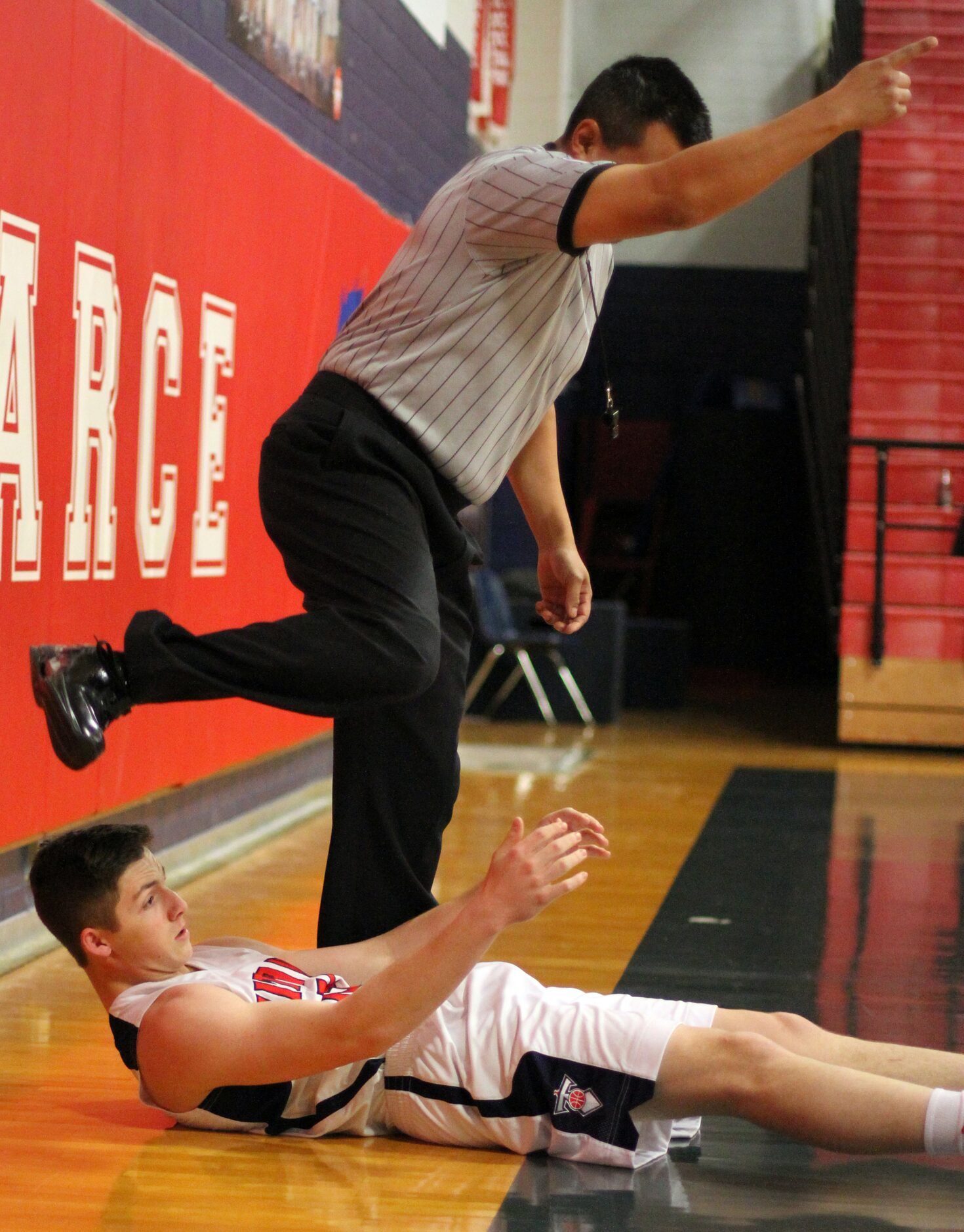 A referee steps over Frisco Centennial guard Nolan Richie (15) after ending up on the floor...