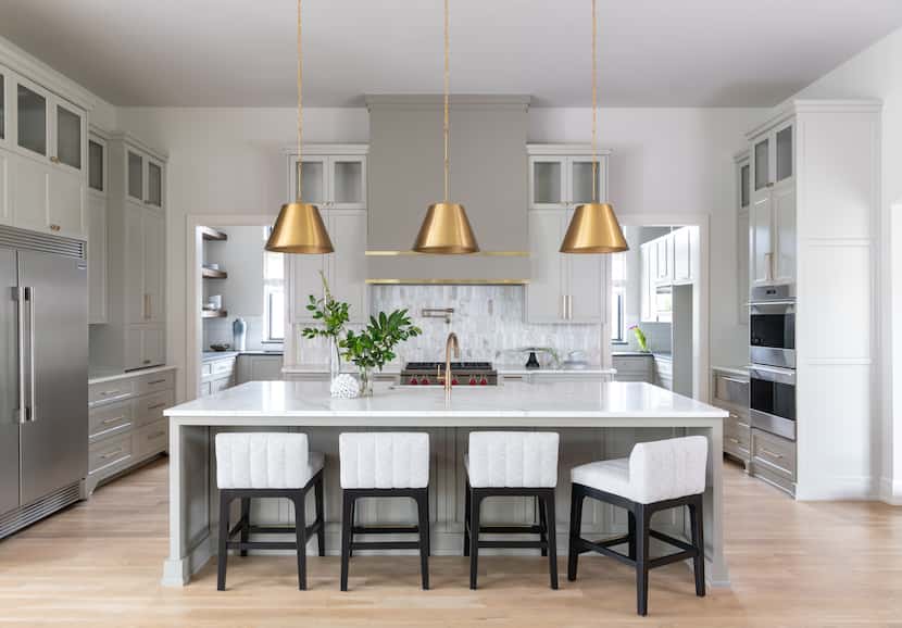 A white kitchen with gold pendants above the island.