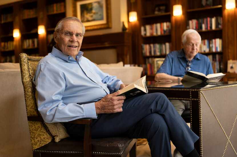 Don Spies reads a book in a reading room across from another man reading a book.