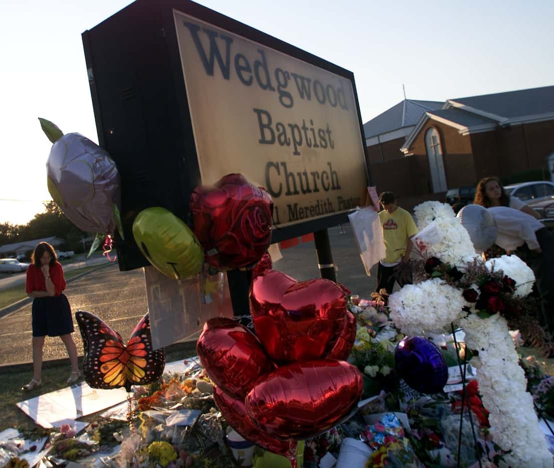 People visit the makeshift memorial at the Wedgwood Baptist Church sign in Fort Worth.
