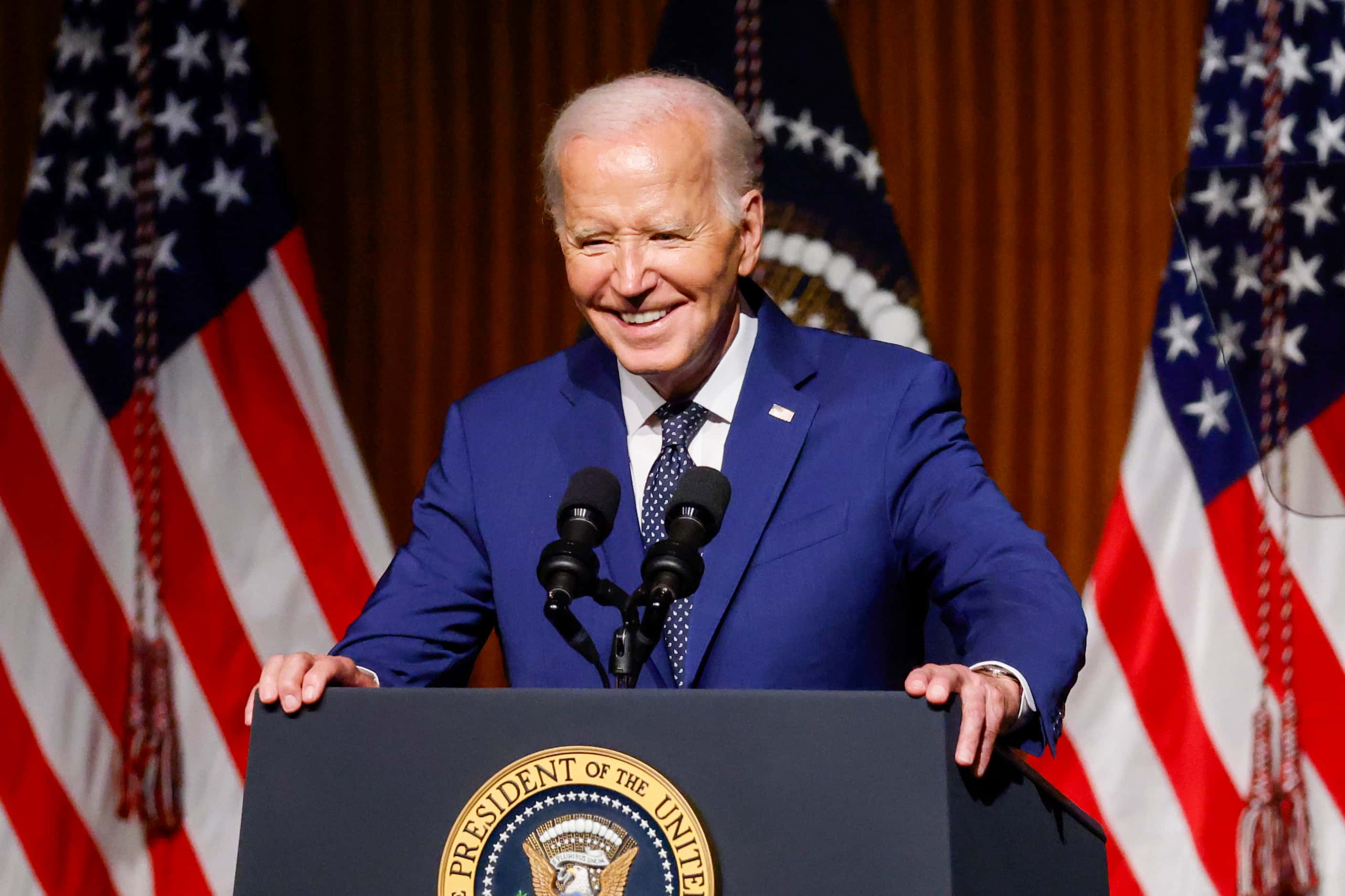 President Joe Biden smiles as he takes the podium to deliver the keynote address during an...